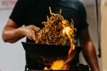 A caucasian man cooking street food in a food truck. Wok. Unfocused