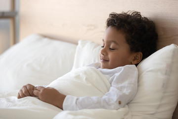 Wall Mural - Cute little biracial boy sleeping in cozy bed at home