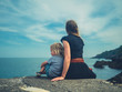 © LoloStock - Young mother and toddler sitting on rocks by the sea