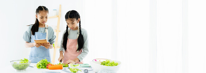 Concept of a culinary school. Two Asian girls are learning to make salad. By looking at tablet taught in the social world Which was done with fun and happiness and happiness And also earning money too