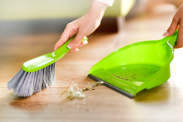 Woman cleaning and sweeping floor at home in modern living room. Housekeeping concept.