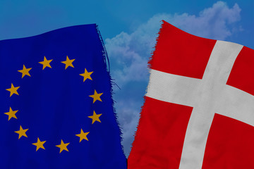 two colored flags on torn fabric, a symbol of international relations between the European Union and Denmark, the concept of global business, the deterioration of political and economic relations