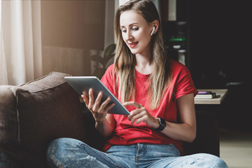 Wall Mural - Girl watching interesting content on tablet connected to Internet. Young woman sitting at home, using mobile device for work or leisure. Entertaining and business content, media resources for users.