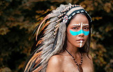 The Abstract Art Design Bakcogrund Of  Beautiful Woman Wearing Headdress Feathers Of Birds. American Indian Girl In Native Costume,posing In Forest,vintage And Art Tone,blurry Light Around