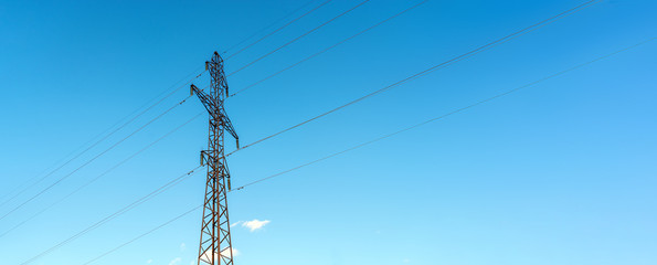 high voltage electrical support. Clear blue sky with cumulus clouds in the background. The energy industry. The current goes through the wires. Free space for text.