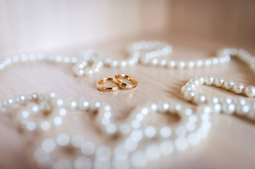 Wall Mural - A pair of gold wedding rings in the white pearl background. Closeup.