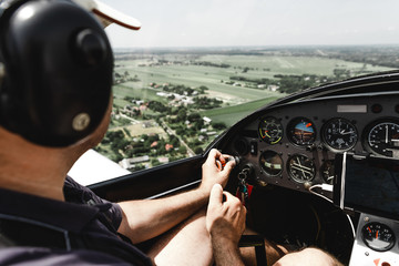 View from pilot's cabin. Control panel. Close up of a pilot flying airplane over the fields and village. Many buttons, navigation devices on dashboar