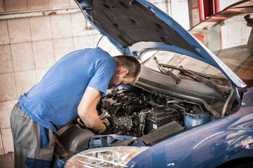 Car mechanic repairer service technician checks and repairs auto engine