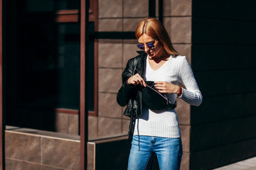 Wall Mural - Stylish model girl at the city in black leather jacket and white sweater and glasses with waist bag