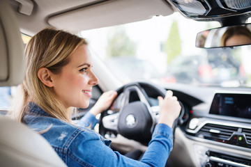 Young woman driver sitting in car, driving.