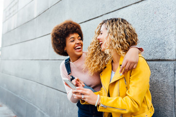 Beautiful lesbian couple using a mobile in the street