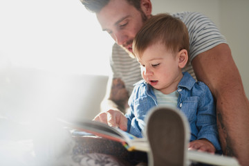 Adorable, young female toddler learning to read book with handso