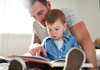 Adorable, young female toddler learning to read book with handso