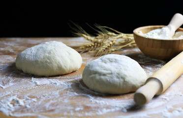 Wall Mural - Pasta fresca pronta per la cottura con spighe di grano su tavolo di legno infarinato. 