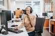 Portrait of beautiful smiling female call-center agent with headset working on support in the office.