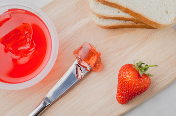 Strawberry jam. Making sandwiches with strawberry jam. Top view. Bread and strawberry jam on a white table with jar of jam and fresh strawberry.