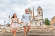 Elegant tourists couple walking down Spanish Steps in Rome, Italy. Europe luxury travel vacation romantic people holding hands on famous tourist attraction romance holiday. Asian woman, Caucasian man.
