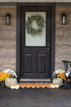 Front Porch Decorated For Thanksgiving Day With Homemade Wreath Hanging On Door. Heirloom Gourds,  White Pumpkins, And Mums Giving An Inviting Atmosphere.