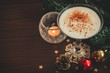 Traditional christmas eggnog with fir branch, burning candle, two balls on wooden background