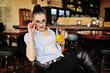 © Evgeniy Kalinovskiy - a beautiful young girl with glasses is holding a mug with beer or a beer orange cocktail in front of a bar or a pub