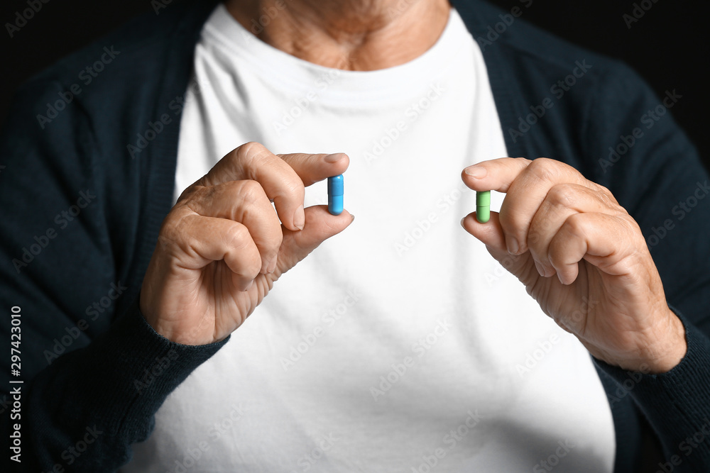 Elderly woman with pills on dark background, closeup