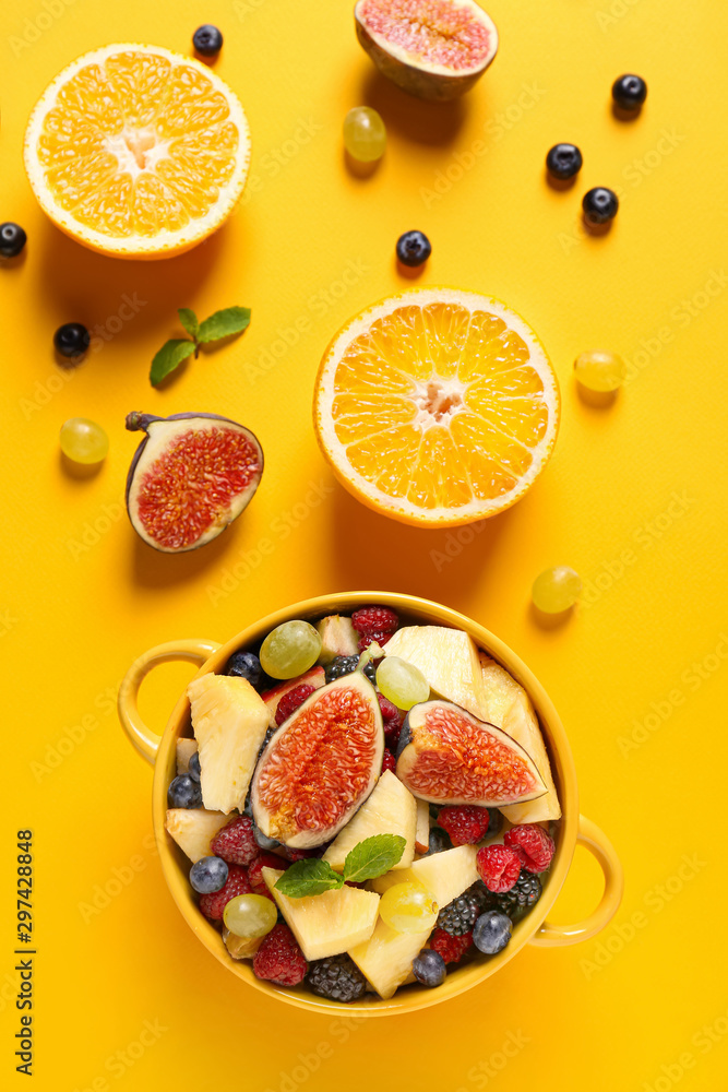 Pot with tasty fruit salad on color background