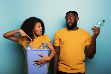 Wall Mural - Happy couple hold a plastic container with bottles over a light blue color. Concept of ecology, conservation, recycling and sustainability