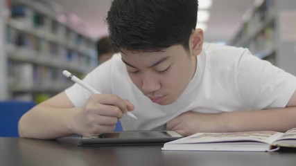 Wall Mural - Asian preteens boys using tablet computer at library . Two boy drawing on tablet computer with smile face.