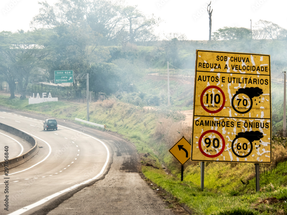 Signpost indicating speed limit on dry and wet roads on Comandante João Ribeiro de Barros Highway, SP 294, near the entrance of Jafa district, in Garca municipality - obrazy, fototapety, plakaty 