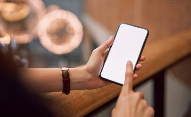 Woman holding and touch smartphone blank screen in the mall. Take your screen to put on advertising.