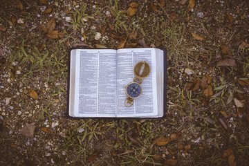 Overhead shot of an open book with an open compass on it on the ground