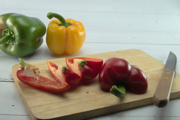 Wall Mural - Closeup  fresh  Red, Yellow, Green, bell pepper or sweet pepper or capsicum  isolate slice on  chopping wood on white background ,raw food ingredient concept.