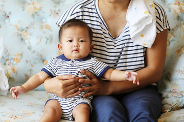 Asian baby with mother in same shirt on sofa. Mother and son.