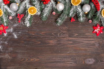 Wall Mural - Christmas greeting card with decor and fir tree branch on a dark wooden background. Top view with copy space for your greetings