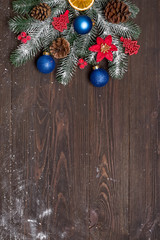 Wall Mural - Christmas greeting card with decor and fir tree branch on a dark wooden background. Top view with copy space for your greetings