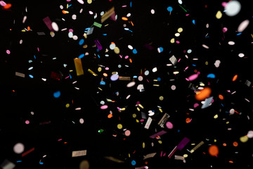 colorful party confetti flying in front of black