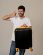 © SB Arts Media - Stylish handsome man showing suitcase. Advertising storage space for travelers and tourism image.