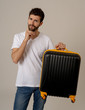 © SB Arts Media - Stylish handsome man showing suitcase. Advertising storage space for travelers and tourism image.