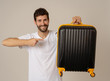 © SB Arts Media - Stylish handsome man showing suitcase. Advertising storage space for travelers and tourism image.