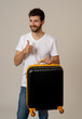 © SB Arts Media - Stylish handsome man showing suitcase. Advertising storage space for travelers and tourism image.
