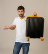 © SB Arts Media - Stylish handsome man showing suitcase. Advertising storage space for travelers and tourism image.
