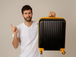 © SB Arts Media - Stylish handsome man showing suitcase. Advertising storage space for travelers and tourism image.