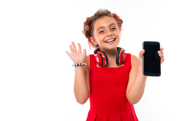 Teenage girl with long blonde hair, dyed tips pink, stuffed in two tufts, in red dress, with red headphones, bracelet, standing and holding phone in hand and smiles