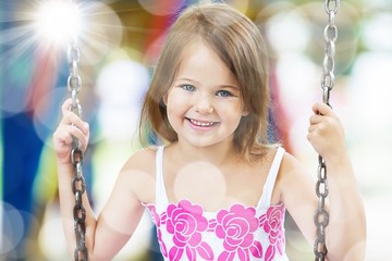 Little child blond girl having fun on a swing