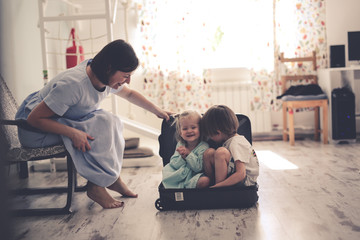 Wall Mural - funny children hide in suitcase near mom