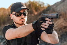 Portrait Of A Young Man Shooting A Hand Gun Outdoors, Close-up.