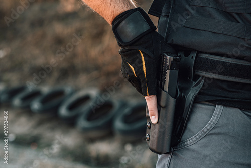 Fotografía Pulling out a gun from the holster on belt, close-up.