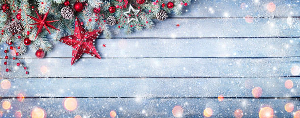 Christmas Fir Branches On Wooden Blue Plank With Red Baubles And Snowfall