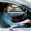 © LIGHTFIELD STUDIOS - selective focus of cheerful bearded driver sitting on car and touching display