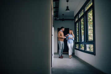 Returning to work after coffee break. Two smiling employees and talking while walking through the office building.